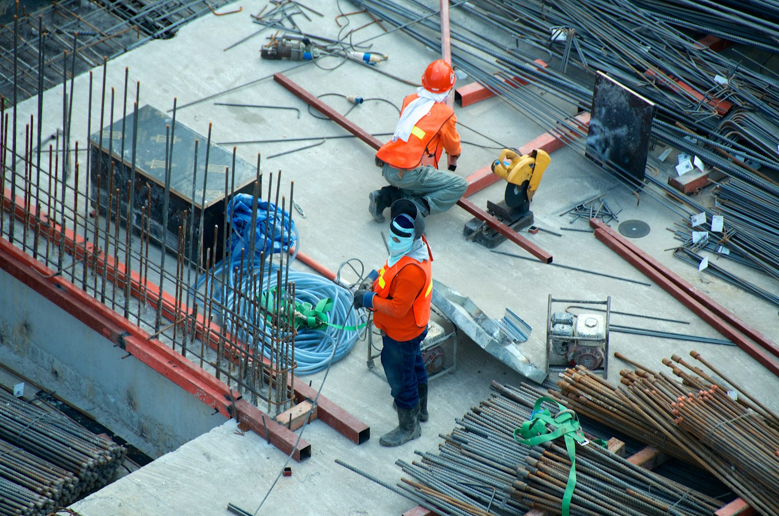 Construction workers in safety gear executing structural concrete works on a large building site